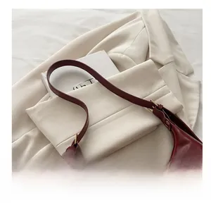 Detail of the reddish brown oil wax leather shoulder bag with adjustable strap on a blazer