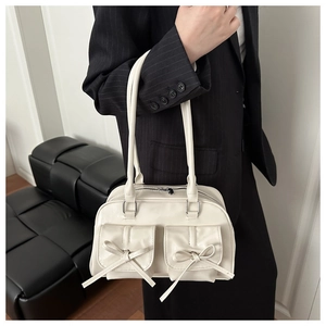 Detail of cream white faux leather underarm bag with decorative bows and twin pockets