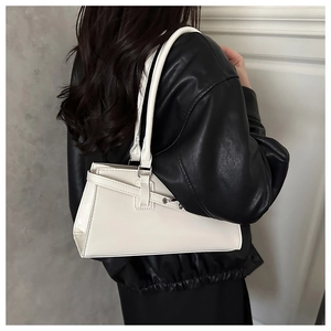 Detailed view of white trapezoid shoulder bag with decorative buckle on black leather jacket