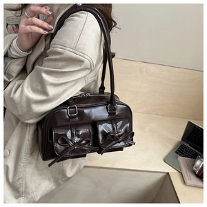 Detail of burgundy patent leather bag featuring ballet-style bows and exterior flap pockets