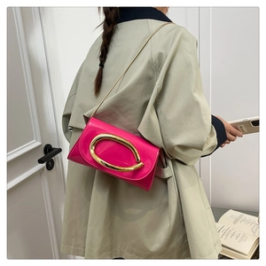 Close-up of fuchsia patent leather handbag with gold oval clasp and chain strap