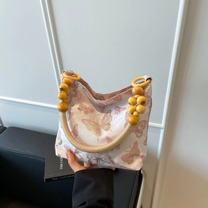 Beigefarbene Tragetasche mit Schmetterlingsstickerei und gelbem Perlenhenkel im Kunststil