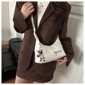 Detail of white half-moon hobo bag with gold zipper and cartoon calf charm on the side