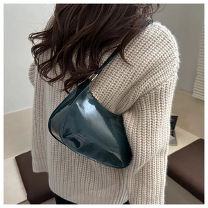 Model view of a dark green patent leather crescent shoulder bag with high gloss finish