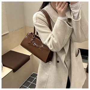 Detail of dark brown leather shoulder bag with vintage silver eyelets and buckle straps