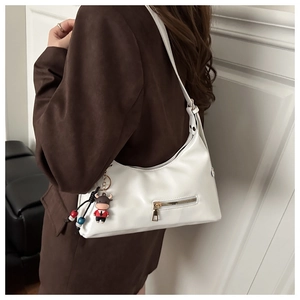 Chic white leather underarm bag featuring a decorative zipper and cute calf doll pendant