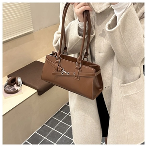 Brown vintage leather shoulder bag styled with an elegant beige coat in a cafe setting