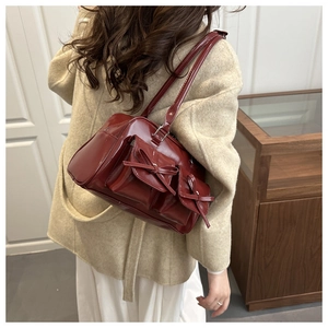 Detail shot of a burgundy PU leather shoulder bag with chic bow accents on side pockets