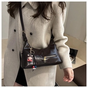 Close-up of brown oiled leather tote with gold zipper and cartoon bull pendant