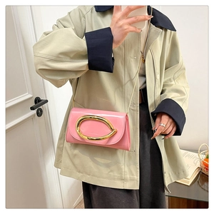 Detail of a bright pink patent leather handbag with a large gold oval buckle and chain