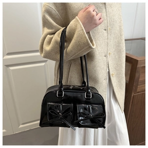Close-up of black patent leather shoulder bag with bow-knot pockets and silver zippers