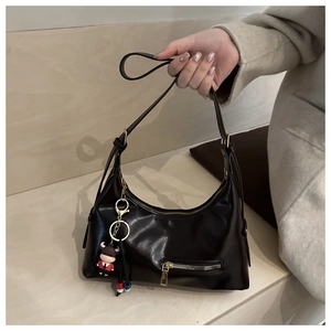 Detail of black semi-circle leather hobo bag with a cute cartoon bull charm accessory
