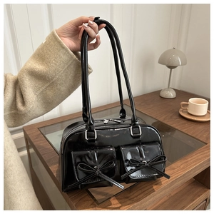 Detail of black patent leather bag featuring elegant double bow pockets and silver zippers