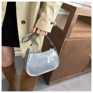 Chic grey glossy patent leather crescent shoulder bag styled with a beige trench coat