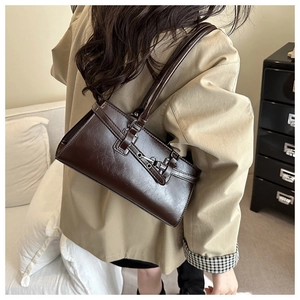 Rear view of a model wearing a brown vintage leather underarm bag with metal buckle
