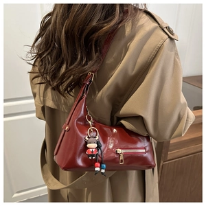 Detail of burgundy glossy leather tote bag with moon shape and cute calf charm