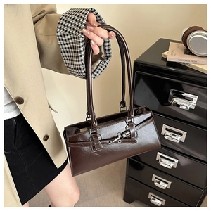 Detail of vintage brown leather underarm bag with metallic buckle and glossy texture finish