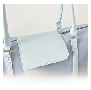 Macro detail of light blue textured fabric with gold metal buckle and leather strap