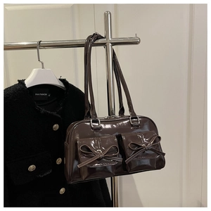 Detail view of dark brown patent leather shoulder bag with bows on silver hanger