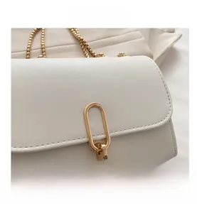 Detail view of white leather bag with gold oval clasp and fine pebbled texture