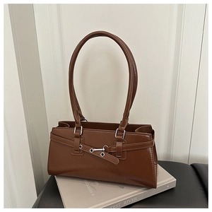 Macro view of caramel brown leather underarm bag featuring silver buckles and dual straps