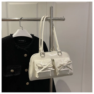 Close-up of cream PU leather shoulder bag featuring glossy finish and bow tie pockets