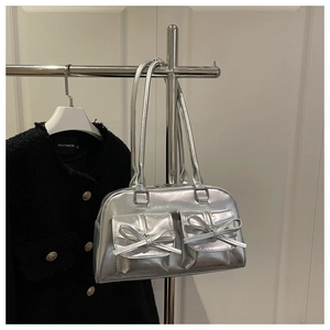 Close-up of metallic silver Y2K shoulder bag with twin bow details and front pockets