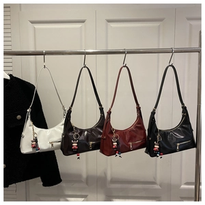 Polished faux leather hobo bags in four colors with doll pendants on a metal rack