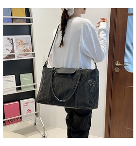 Side view of large black travel bag with crinkle texture and dual handle straps