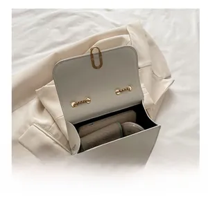 Interior capacity of creamy white leather crossbody bag with gold buckle showing essentials