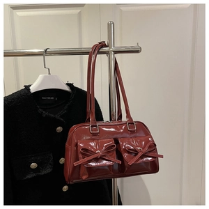 Detail of red patent leather shoulder bag with chic bow accents and dual front pockets