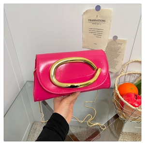Detail of fuchsia patent leather handbag with gold C-buckle and elegant chain strap