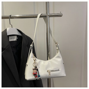 Detail of white PU leather tote with a metal zipper pocket and a cute cow doll charm