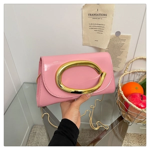 Detail of pink patent leather handbag with gold metal clasp and chain strap