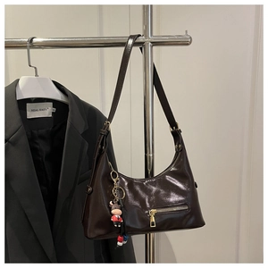 Close-up of a vintage dark brown oil wax leather tote bag with a cute cartoon cow charm
