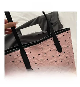 Gros plan du sac cabas rose en tissu crépon avec imprimés nœuds et anses en cuir