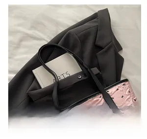 Détail du sac cabas rose avec motifs nœuds noirs et texture plissée sur blazer gris