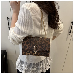 Detail of leopard print crossbody bag with gold U-shaped buckle and metal chain strap