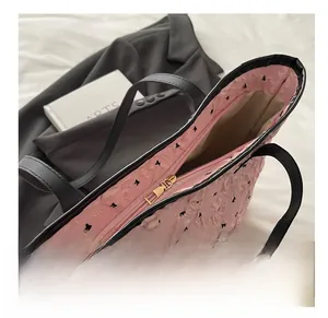 Détail du sac cabas rose à texture bulle avec fermeture dorée et motif nœud noir