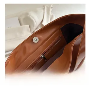 Dettaglio della borsa tote marrone con fodera in tessuto, tasca zip e chiusura magnetica