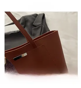 Detail of a brown leather tote bag with silver trim and an elegant patterned silk scarf