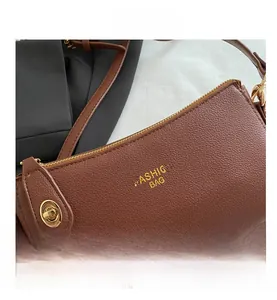 Close-up of brown litchi grain leather texture and gold metal hardware on the crossbody bag