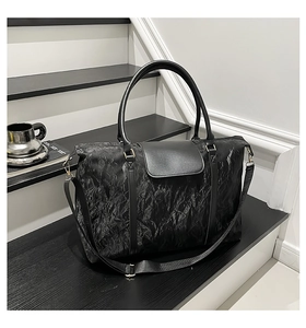 Detail of black textured travel tote with premium leather handles and adjustable strap