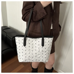 Détail d'un sac cabas matelassé blanc avec petits nœuds noirs et fines bandoulières en cuir