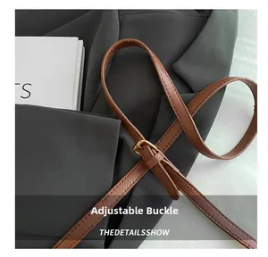 Detail of adjustable gold buckle on brown leather strap with fine stitching