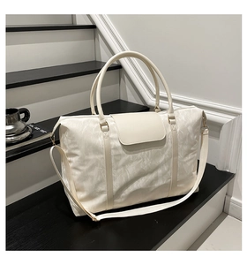 Detailed view of white quilted travel tote on minimalist stairs showing golden hardware