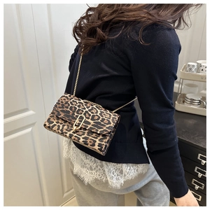 Detail of leopard print crossbody bag with gold chain strap worn by a model in lifestyle shot