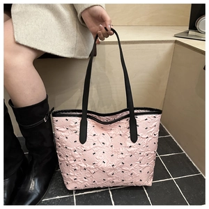 Détail d'un sac cabas matelassé rose orné de petits nœuds noirs élégants