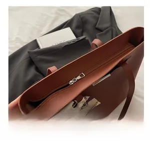 Detail of a brown leather tote with smooth silver zipper and floral silk scarf charm