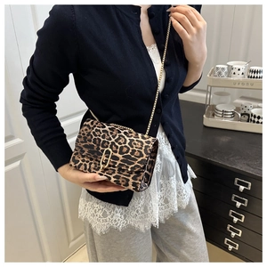 Fashionable leopard print crossbody bag with gold chain and metal buckle detail on model